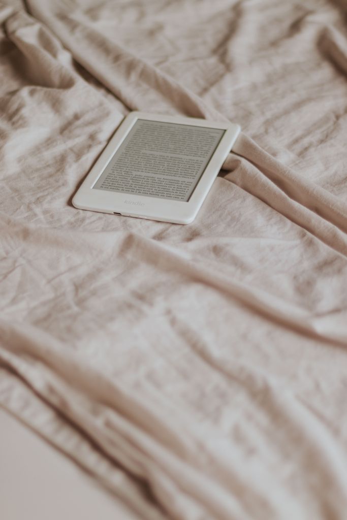 A sleek e-reader device resting on crumpled beige fabric, ideal for reading enthusiasts.