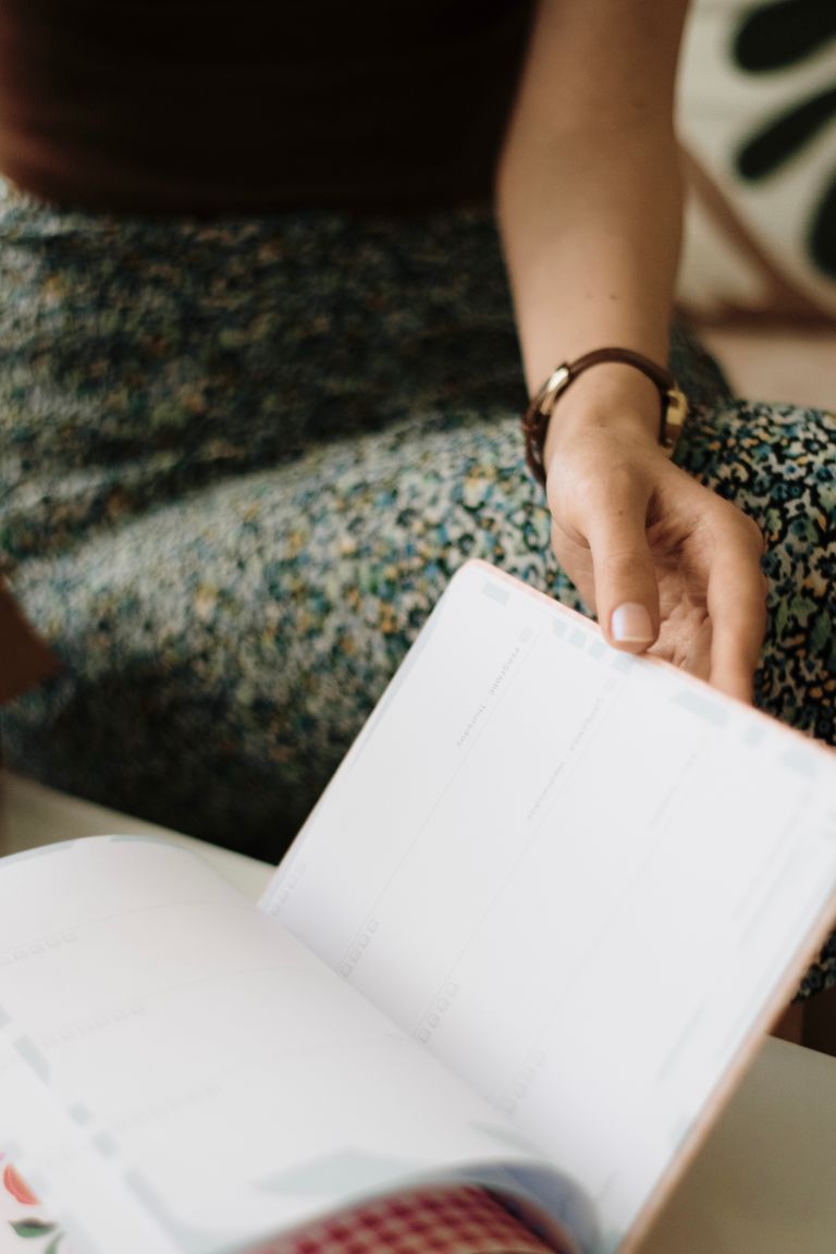 Young woman relaxing indoors with an open planner, focusing on leisure and organization.